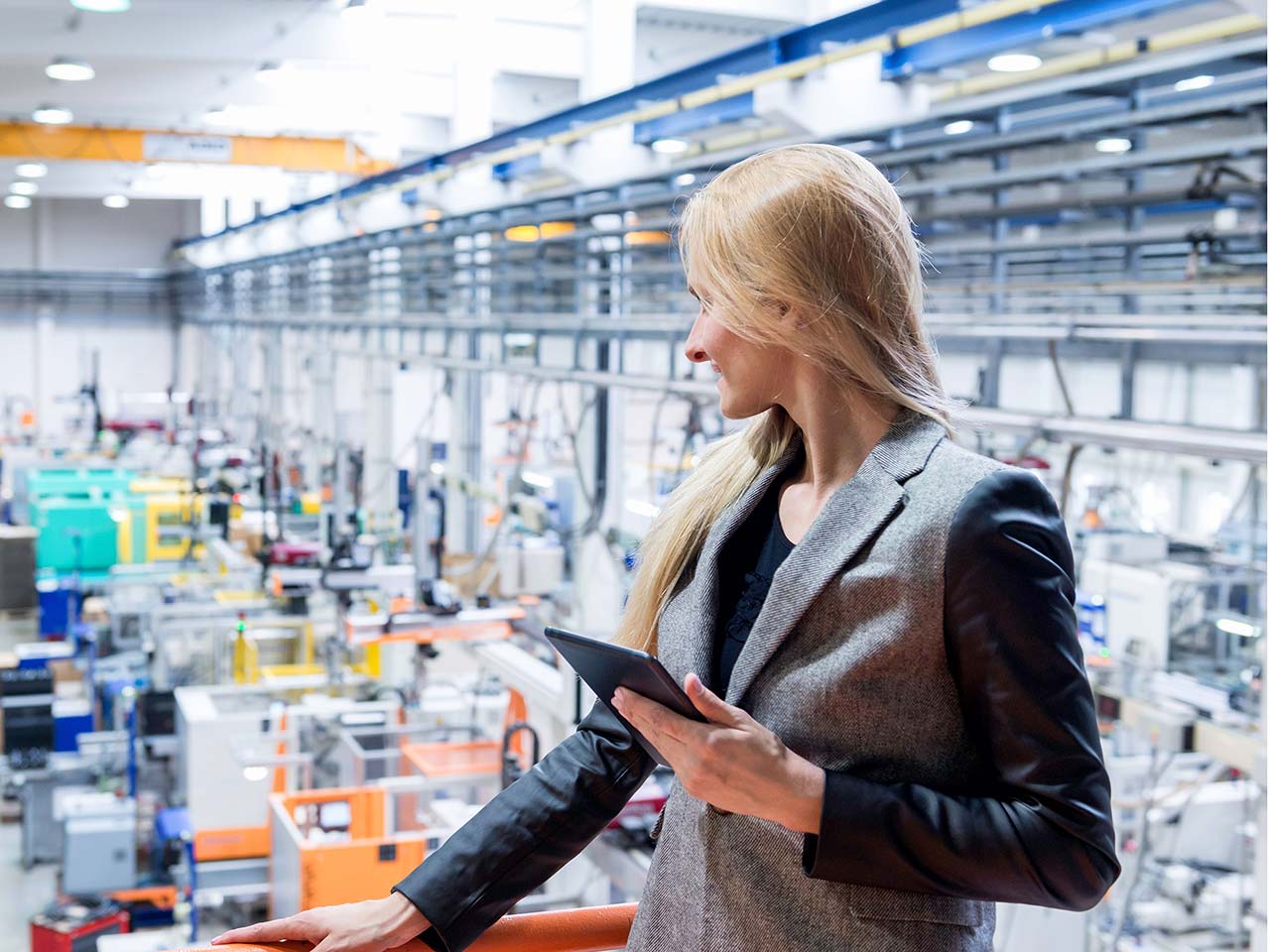 Woman working on a tablet looking out on factory floor